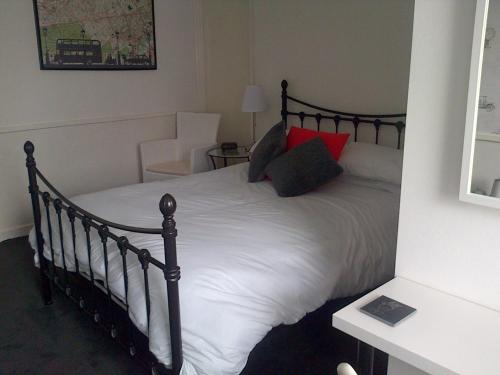 a bedroom with a bed with white sheets and red pillows at Lewinsdale Lodge in Weston-super-Mare