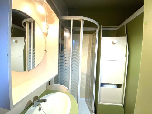 La salle de bains est pourvue de toilettes et de 2 miroirs. dans l'établissement Charmant chalet situé dans un camping 4 étoiles - 4 à 6 personnes - TILIO, à Guidel