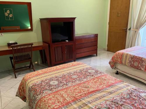 a bedroom with a bed and a dresser and a television at Puri Sawo Manila in Jakarta