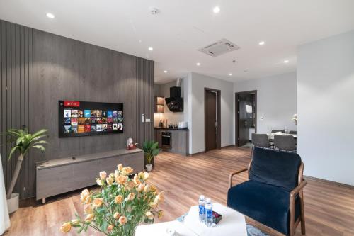 a living room with a couch and a tv on a wall at Luxe Paradise Suites Hotel To Ngoc Van in Hanoi