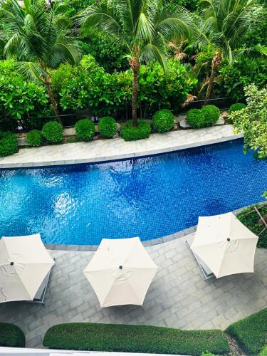a pool with two white umbrellas next to a swimming pool at Cozy Paradise By Rawai Beach in Phuket