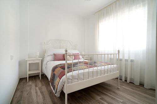 Un dormitorio blanco con una cama y una ventana. en GALIHOST - Casa de Cruces, en Villanueva de Arosa