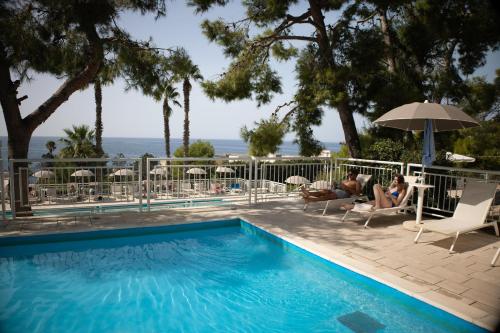 a swimming pool with people sitting in chairs and an umbrella at Grand Hotel Riviera - CDSHotels in Santa Maria al Bagno