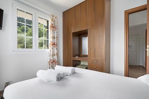 a bedroom with a white bed and a window at Monte Verde apartments in Lixouri