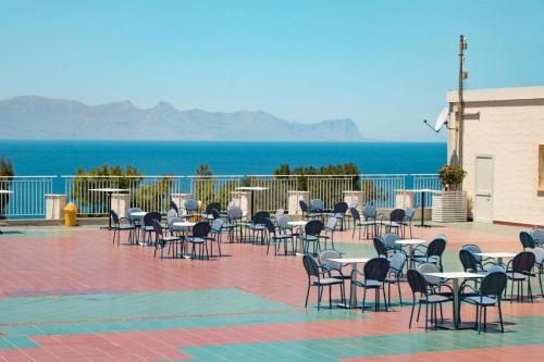 a group of tables and chairs with the ocean in the background at CDSHotels Terrasini - Città del Mare in Terrasini