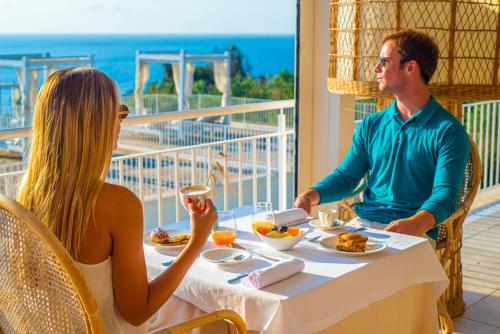 a man and a woman sitting at a table with food at Marenea Suite Hotel - CDSHotels in Marittima