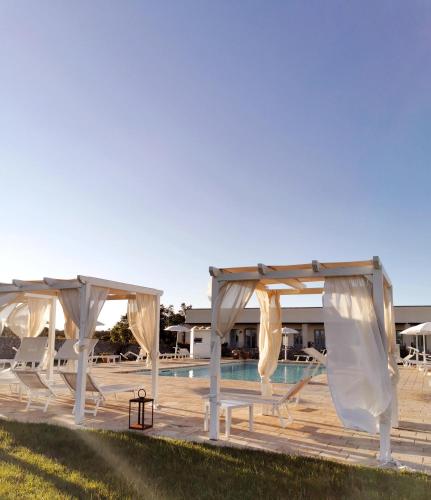 a pool with two white pavilionitures and a pool at Relais Masseria Le Cesine - CDSHotels in Vernole