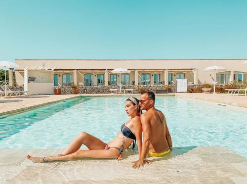 a man and a woman sitting in the swimming pool at Relais Masseria Le Cesine - CDSHotels in Vernole