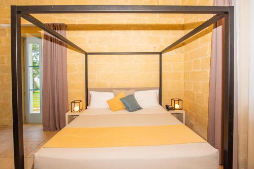 a bedroom with a canopy bed with two lamps at Relais Masseria Le Cesine - CDSHotels in Vernole
