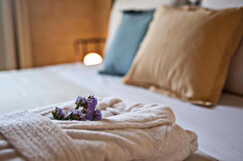 a towel with purple flowers on top of a bed at Relais Masseria Le Cesine - CDSHotels in Vernole