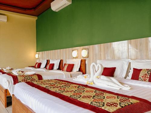 two beds in a hotel room with swans on them at Amed Cafe & Hotel Kebun Wayan in Amed