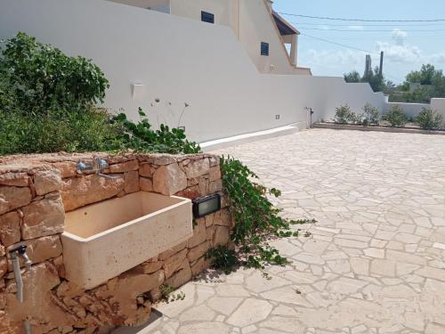 a stone wall next to a building with a stone courtyard at VILLA IL PIGNO ZONA MALDIVE DEL SALENTO in Marina di Pescoluse