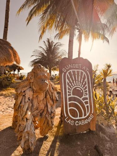 a sign on a beach with a palm tree at Sunset at Las Cabanas in El Nido