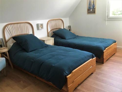 - 2 lits avec des draps bleus dans une chambre dans l'établissement Maison avec jardin, WIFI à 600m de la mer à TREGASTEL - Réf 58, à Trégastel