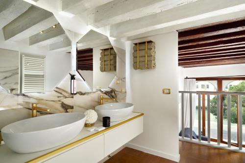 a bathroom with two sinks and a large window at Swan DolceVita Prestige Stay - Canal View & Exclusive Experience in Venice