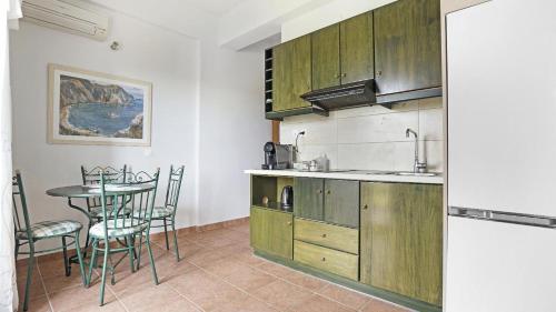 a kitchen with wooden cabinets and a table with chairs at Monte Verde apartments in Lixouri