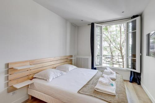 une chambre blanche avec un grand lit et une fenêtre dans l'établissement Bluestay 846 - Superbe appartement, à Paris