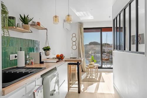 Il comprend une cuisine blanche avec un comptoir et un balcon. dans l'établissement My little Port Grimaud, à Grimaud