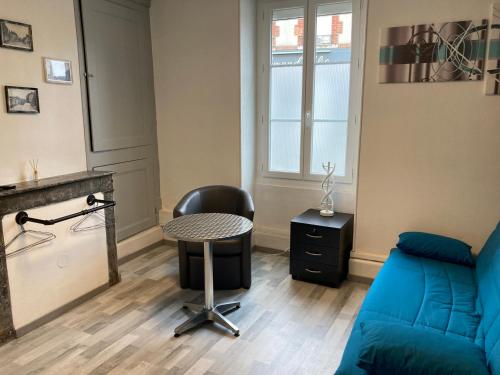 a living room with a blue couch and a table at Meublé F2 au RDC in Ouzouer-sur-Loire