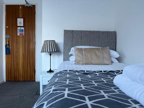 a bedroom with a bed with a headboard and a lamp at The Paddocks Hotel in Symonds Yat
