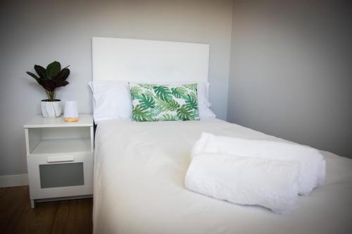a bedroom with a white bed with a plant on it at Playa del Silencio 1 in Castañeras