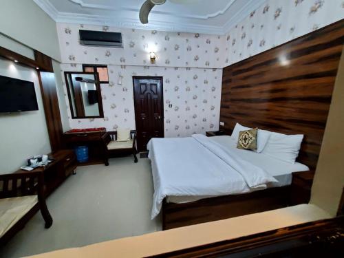 a bedroom with a white bed and a wooden headboard at Karachi Guest House in Karachi