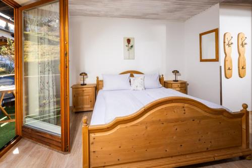 a bedroom with a wooden bed and a glass door at Sportpension Färbinger in Berchtesgaden
