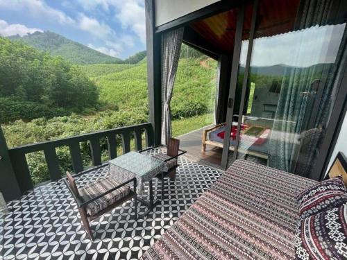 a balcony with a table and a bench and a view at Free Yoga Center - Nguyen Shack in Phong Nha