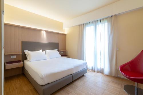 a bedroom with a white bed and a red chair at Là Di Moret in Udine