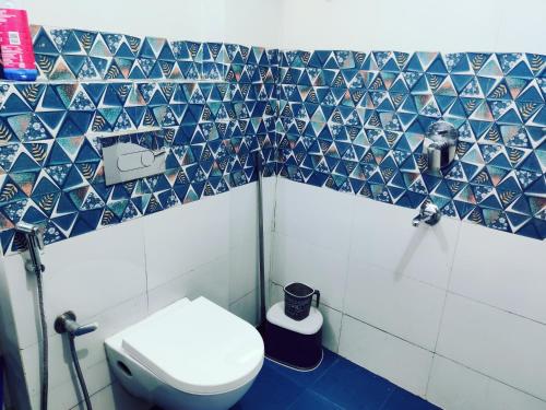 a bathroom with a toilet and blue and white tiles at Heaven Vibes Stays in Rishīkesh
