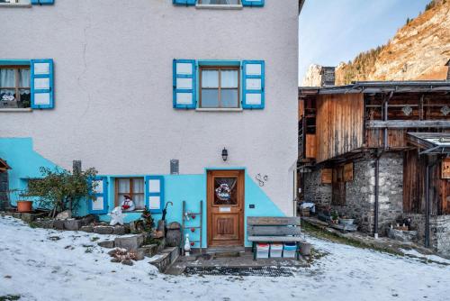a house with blue shuttered windows and a door at Ciesa del Selmo Faure in Sottoguda