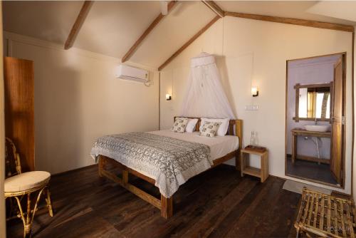 a bedroom with a bed and a chair and a mirror at Ravi Yoga Retreat in Polem