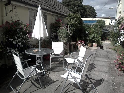 a patio with a table and chairs and an umbrella at Lewinsdale Lodge in Weston-super-Mare