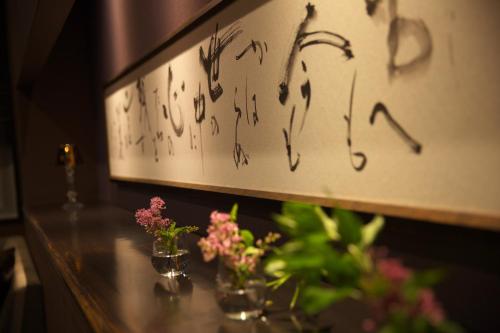 a table with two vases of flowers on a wall at Matsuya Bekkan in Kumamoto