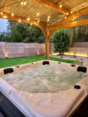 a hot tub in a backyard under a pergola at Au coeur des désirs in Tétaigne