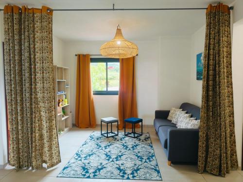 Una sala de estar con un sofá y dos taburetes. en Villa ALAMANDA - Les Emeraudes du Guillaume, en Saint-Paul