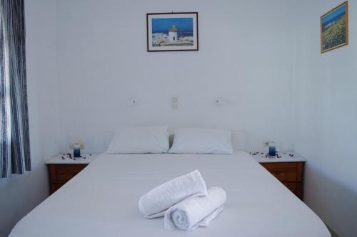 Un dormitorio con una cama blanca con toallas. en Sunlight Kastraki beach house, en Naxos Chora