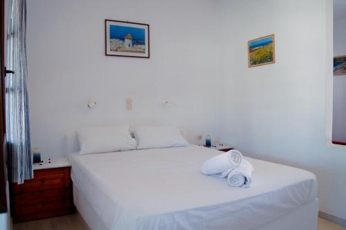 Un dormitorio con una cama blanca con toallas. en Sunlight Kastraki beach house, en Naxos Chora