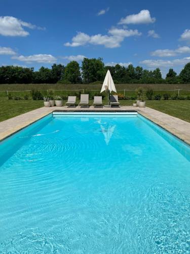 - une piscine d'eau bleue et 2 chaises dans l'établissement Domaine de La Lipomerie - LA BERGERIE, à Gâprée