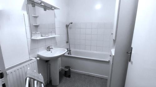 un bagno bianco con lavandino e vasca di Au bord de la riviere a Douzy