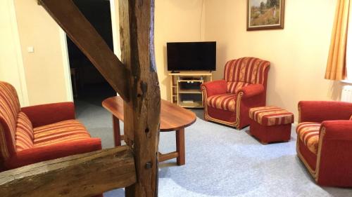 a living room with red chairs and a tv at La ferme de la fontaine in Douzy