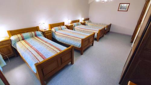 a group of four beds in a room at La ferme de la fontaine in Douzy