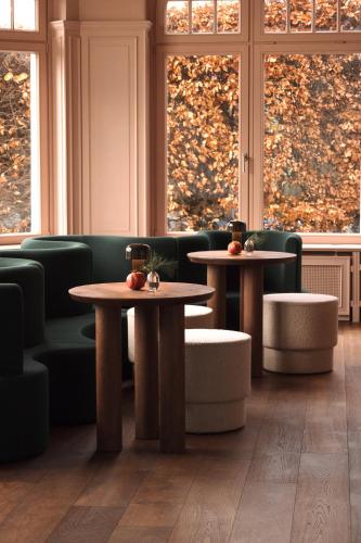 two tables and chairs in a room with windows at stilwerk Strandhotel Blankenese in Hamburg