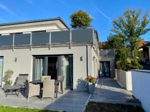 a white house with a patio with chairs and a table at Ferienwohnung Felix in Furth im Wald