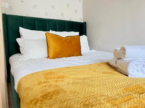 - un lit avec une tête de lit verte et des oreillers orange dans l'établissement Porte Du Soleil - Cosy Studio Centre, à Strasbourg