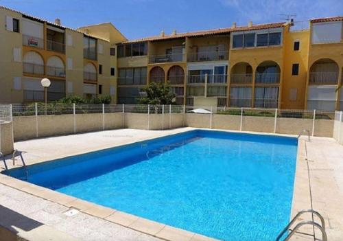 une grande piscine bleue devant un immeuble dans l'établissement NP160-441 Pavillon 2 pièces mezzanine, Narbonne Plage, à Narbonne-Plage
