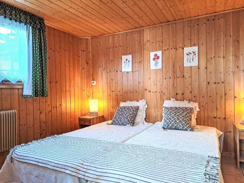 ein Schlafzimmer mit einem Bett in einer Holzwand in der Unterkunft Apartment Rousserolles rez gauche by Interhome in Verbier