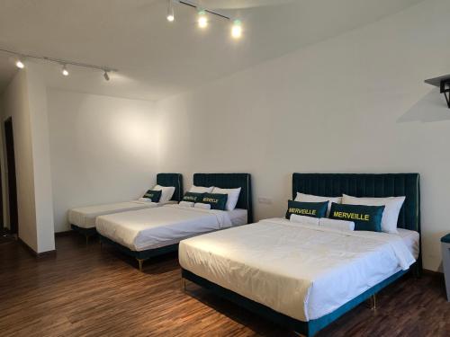 two beds in a room with white walls and wood floors at K Avenue Kota Kinabalu by Merveille - Sabah in Donggongon