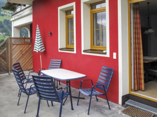 a table and chairs in front of a red wall at Apartment Lechners Wohnwelt-3 by Interhome in Stumm
