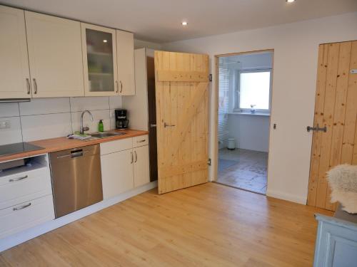 a kitchen with white cabinets and a wooden door at Lindenhof in Ahneby